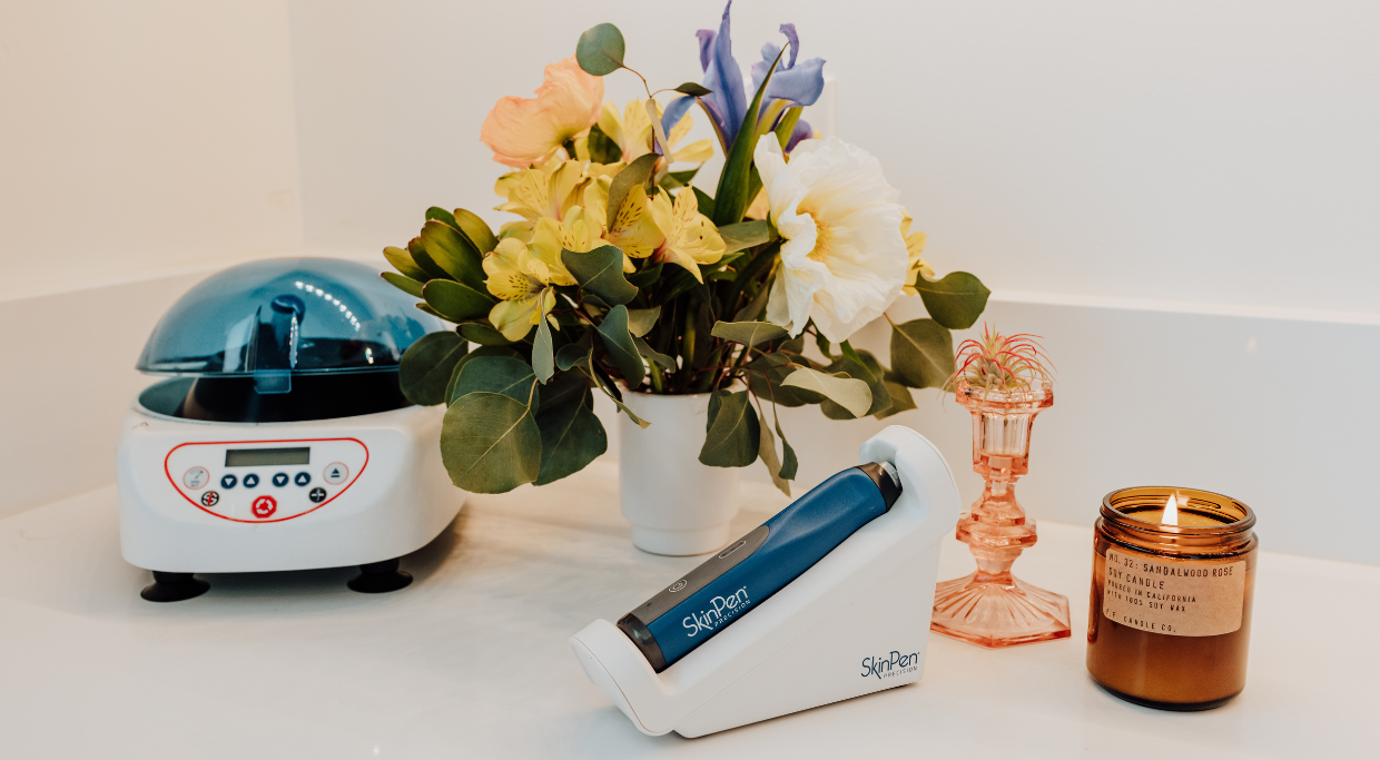 Picture of Skinpen microneedling device and PRF centrifuge with flowers in background and a candle