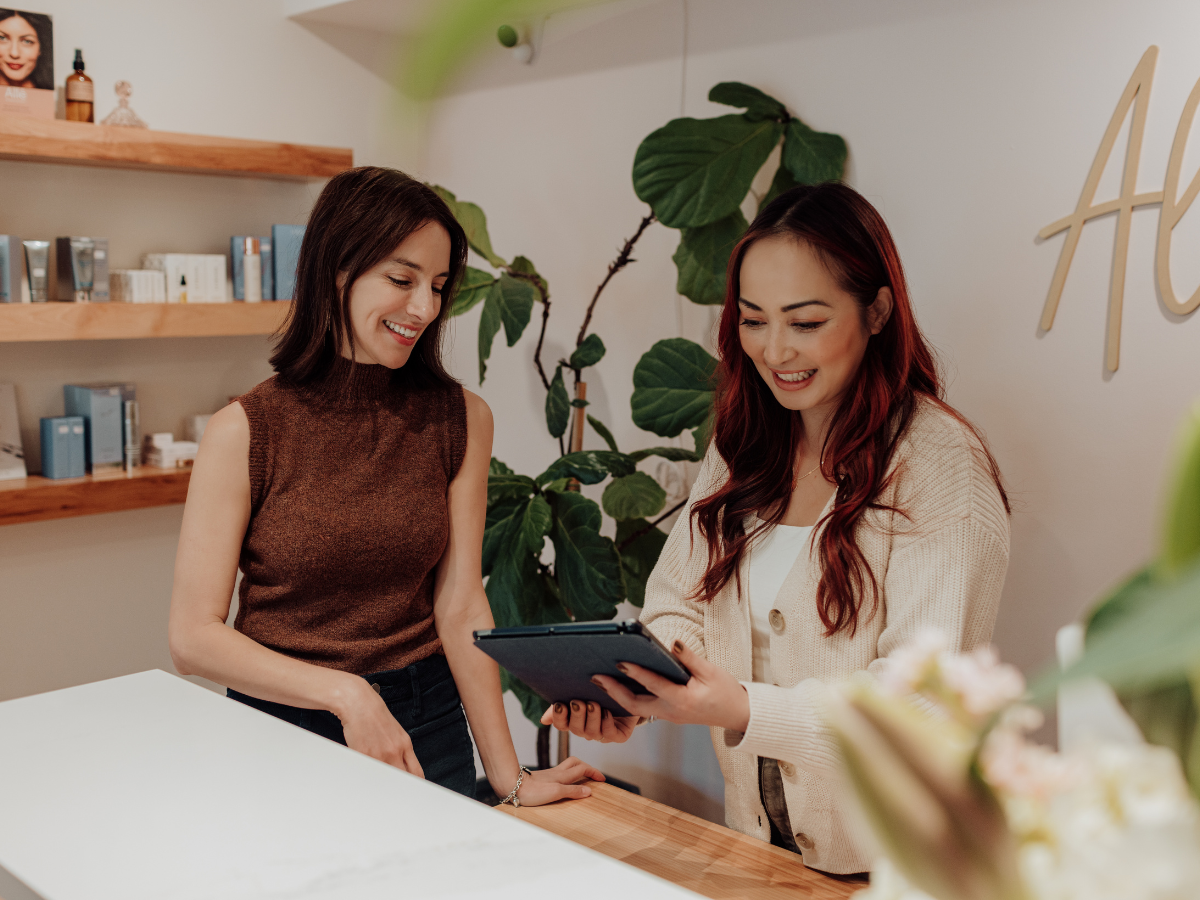 Aimee and Michelle of Aluma Aesthetic Medicine looking at ipad for scheduling clients