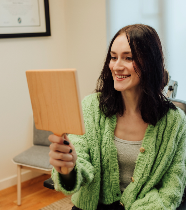 Woman looking in mirror at Sculptra results