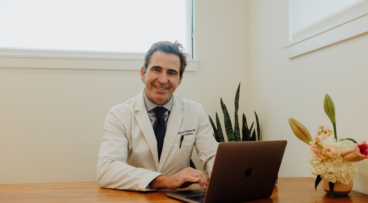 Picture of Dr. Brigham at desk with laptop opened